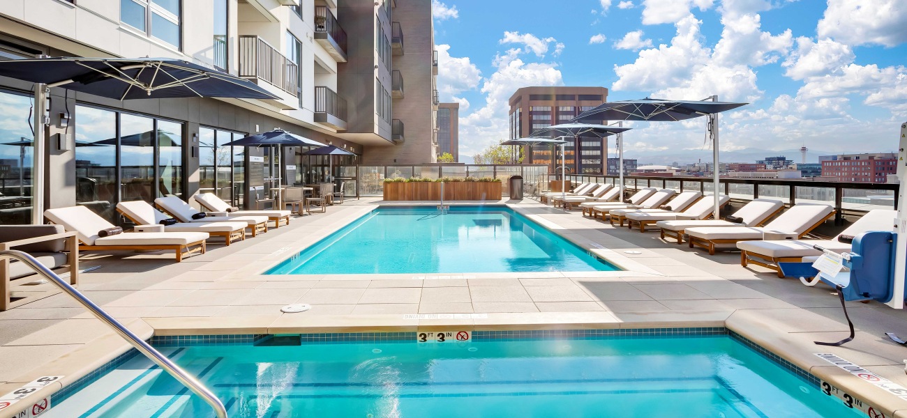 Luxurious rooftop pool area with stunning city views, stylish loungers, and elegant umbrellas under a bright blue sky.	 Luxurious rooftop pool area with stunning city views, stylish loungers, and elegant umbrellas under a bright blue sky.