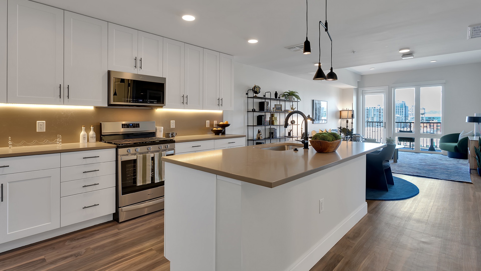 Modern open-plan kitchen and living area with sleek cabinetry, a chic island with bar stools, and large windows offering vibrant city views.	 Modern open-plan kitchen and living area with sleek cabinetry, a chic island with bar stools, and large windows offering vibrant city views.